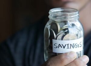 man holding coins in a jar labeled savings